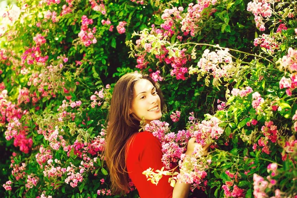 Pretty girl among blossoming flowers — Stock Photo, Image