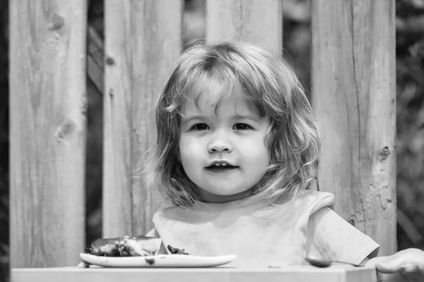 Kleine jongen eten taart in de buurt van houten hek — Stockfoto