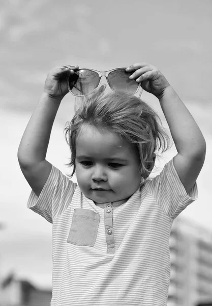 Aranyos baba fiú teszi divatos napszemüveg a fej — Stock Fotó