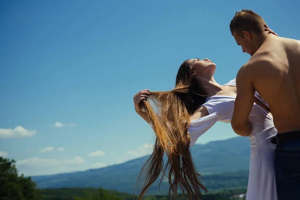 Mann umarmt Frau mit fliegendem langen Haar an sonnigem Tag — Stockfoto