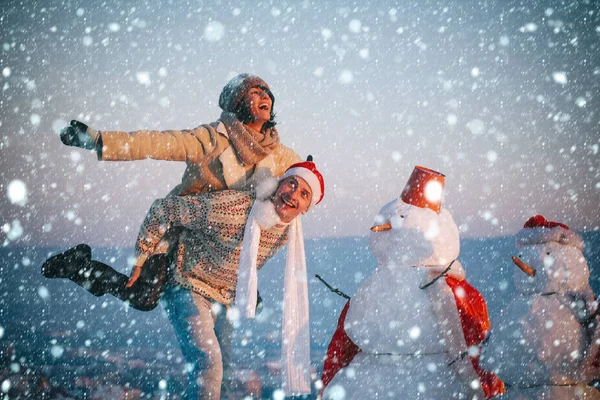 Navidad pareja enamorada de hombre y chica con muñeco de nieve — Foto de Stock