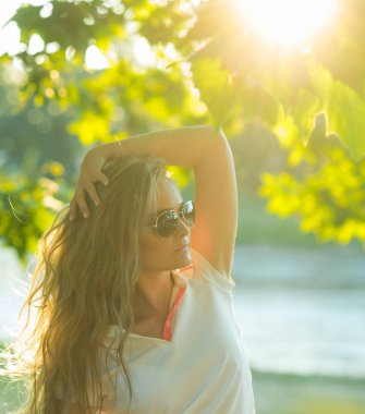 Uzun sarı saçlı kız poz altında yeşil ağaç