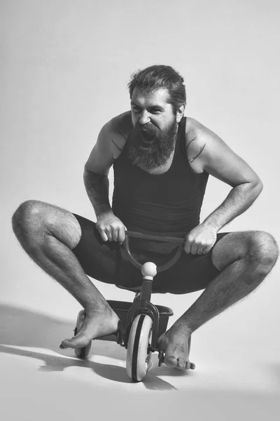 Бородатий кричить щасливий чоловік сидить на барвистій велосипедній іграшці — стокове фото