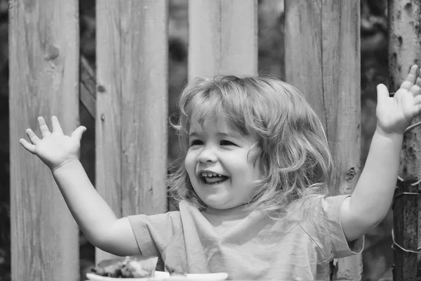 Kleine jongen eten taart in de buurt van houten hek — Stockfoto