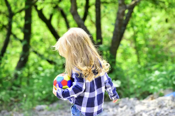 Девочка или мальчик с длинными светлыми волосами играют с мячом — стоковое фото