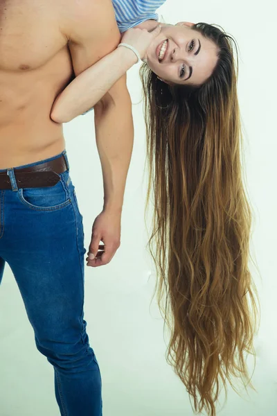 Счастливая женщина с длинными волосами висит на сильном теле — стоковое фото