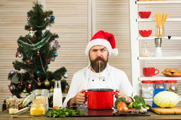Chef man in santa claus hat cooking.