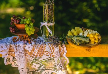 Lavanta çiçek vazo, üzüm ve peynir beyaz masa örtüsü üzerinde