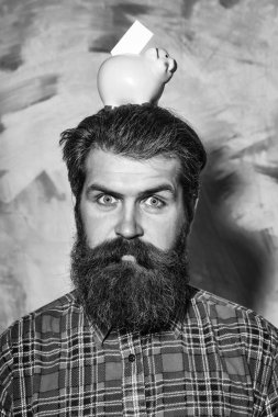 Sakallı adam kafasına pembe seramik kumbara tutan kaşlarını