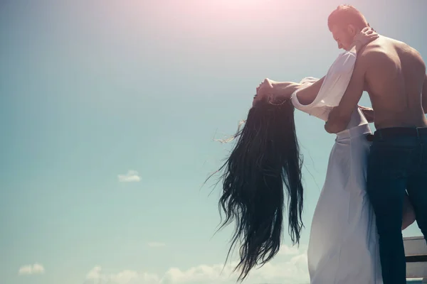Мужчина обнимает женщину с длинными волосами на голубом небе — стоковое фото