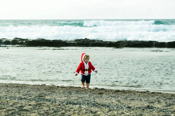 ペブル ビーチの赤いサンタ コートのかわいい男の子 — ストック写真
