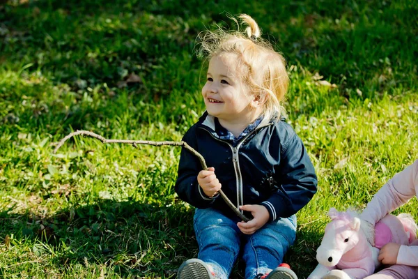 Garçon enfant sourire avec bâton sur l'herbe verte — Photo