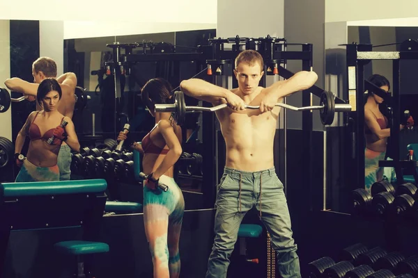 Musculoso hombre y chica en el gimnasio con mancuernas y barra —  Fotos de Stock