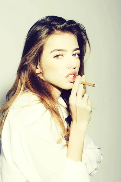 Довольно сексуальная женщина с длинными волосами, курящая сигарету в рубашке — стоковое фото