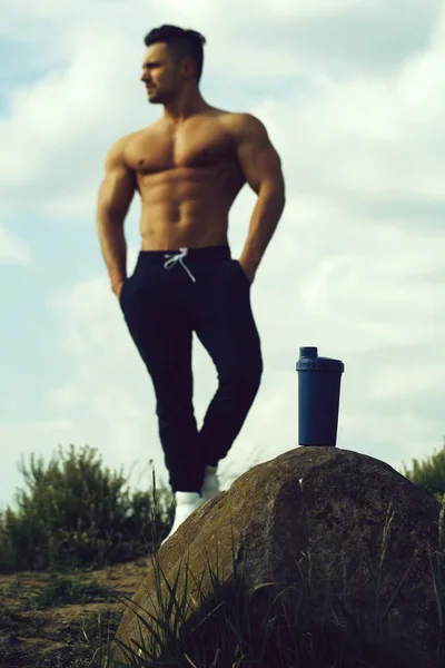 Muscular man posing near water bottle — Stock Photo, Image