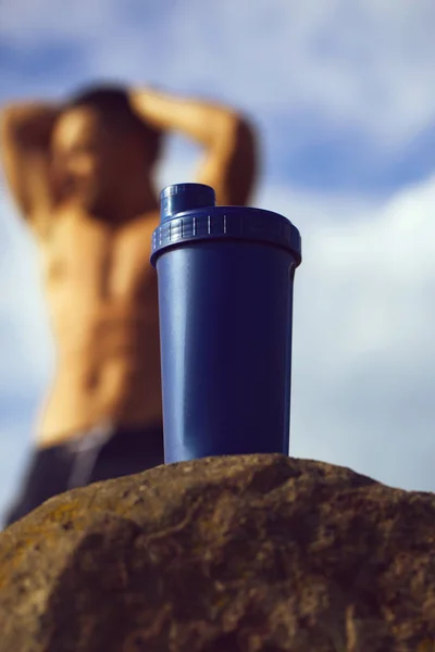 Hombre muscular relajante cerca de botella de agua —  Fotos de Stock