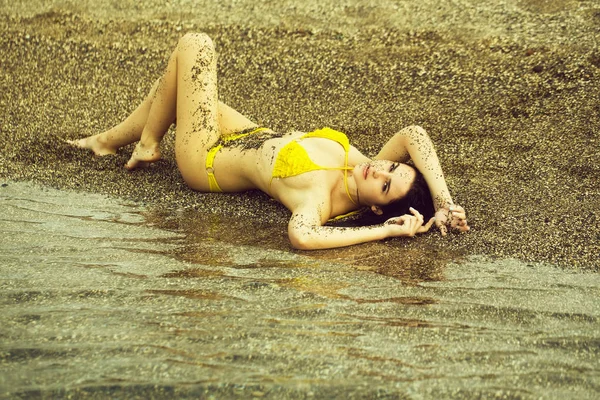 Menina bonita em maiô amarelo deitado na praia do mar — Fotografia de Stock