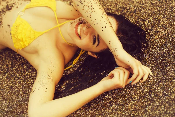 Pretty happy girl lies in yellow swimsuit top on beach — Stock Photo, Image