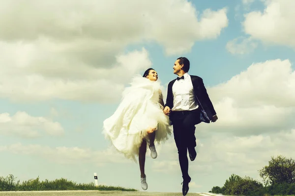 Svatební šťastný pár běžící na silnici — Stock fotografie