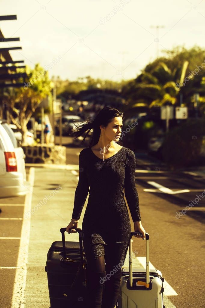 Pretty girl walking and rolling two suitcases