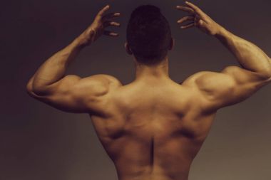 genç yakışıklı maço adam vücut geliştirmeci seksi kaslı atletik vücut çıplak gövde ve gri arka plan üzerinde Studio güçlü sırt ile