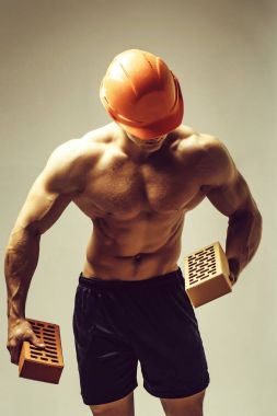 genç yakışıklı maço adam Oluşturucu ile seksi kaslı atletik güçlü vücut çıplak gövde ve güçlü karın altı paketleri ile ya da tuğla abs turuncu baret veya kask tutar