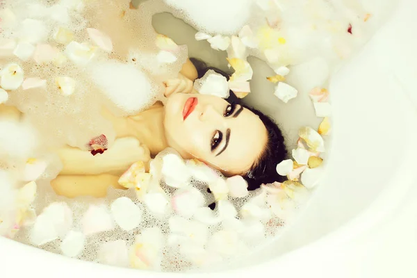 Sexy mujer en baño con pétalos — Foto de Stock