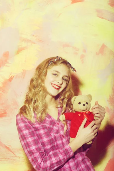 Feliz chica bonita sonríe con lindo oso de peluche en rojo — Foto de Stock