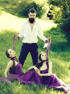 Sakallı adam ve iki kadınla çimenlerin üzerinde