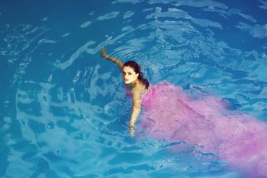 genç seksi kadın veya kız güzel yüzü ve glamour moda pembe elbise yaz günü açık yüzme havuzunda mavi su ile ıslak saç ile