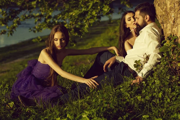 Bebaarde man en twee vrouwen op gras — Stockfoto