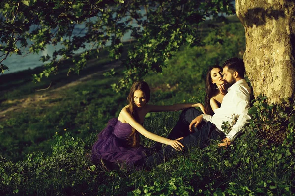 Bearded man and two women on grass — Stock Photo, Image