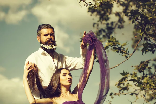 mor elbise güneşli bir gün mavi gökyüzü arka plan üzerine açık sakal ve genç güzel kadın karahindiba çiçeklerle Beyaz tişörtlü yakışıklı adam