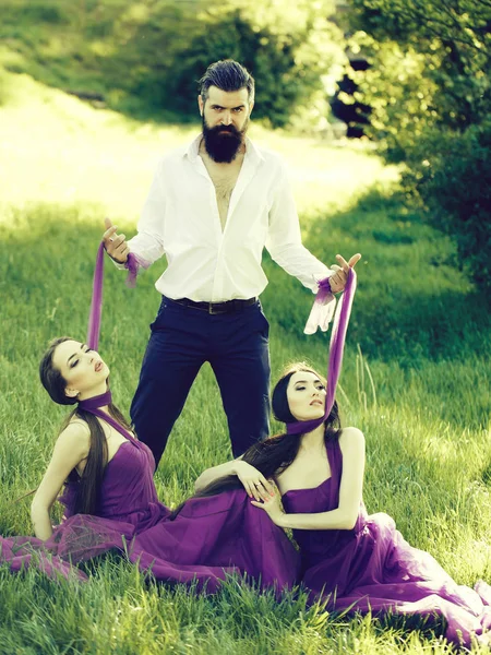 Sakallı adam ve iki kadınla çimenlerin üzerinde