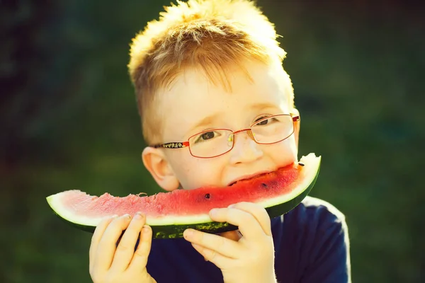 Menino feliz com cabelo vermelho em óculos comendo melancia — Fotografia de Stock