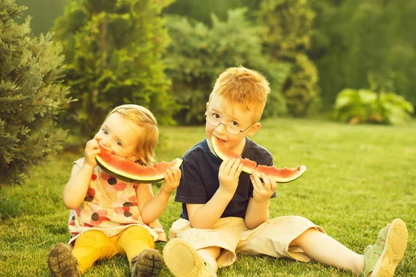 Dzieci jedzenie arbuz czerwony na trawie — Zdjęcie stockowe