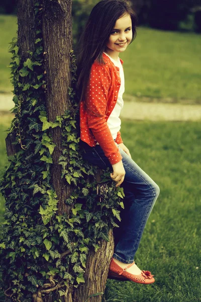 Chica en vestido con cuaderno y pluma cerca del árbol — Foto de Stock