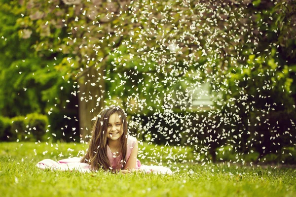 Yaprakları yeşil çimenlerin üzerinde küçük kız