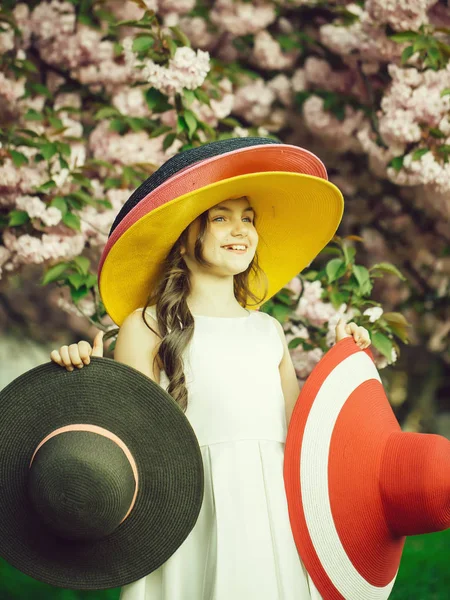 Small girl with hats in park — Stock Photo, Image