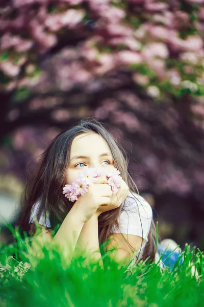 Liten flicka på gräs i blom — Stockfoto