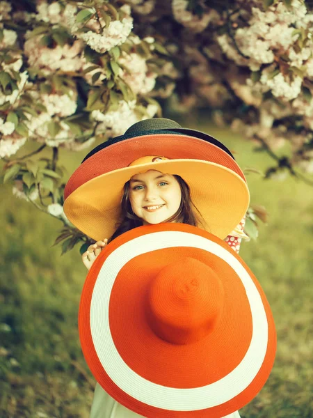 Kleines Mädchen mit Hüten im Park — Stockfoto