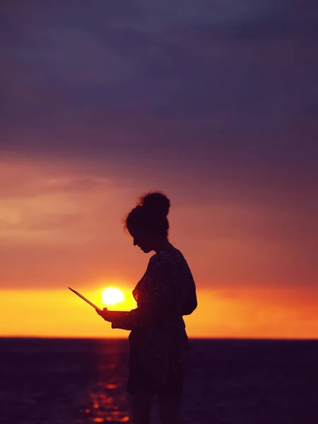 female silhouette with laptop on sunset