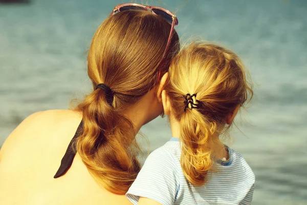 母と息子 美人とかわいい赤ちゃんの少年 青い背景をぼかした写真の日当たりの良い夏の日の海や海の水をブロンドの髪ポニーテール見て — ストック写真