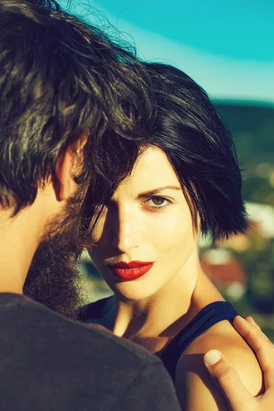 Beautiful woman brunette with red lips and man hipster bearded sensual couple embrace on sunny summer day on nature