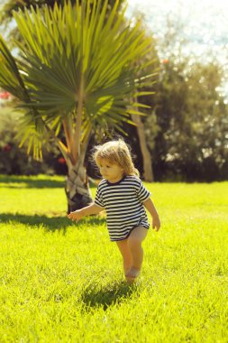Şirin bebek çocuk çizgili tshirt yeşil çimenlerin üzerinde yürüyor