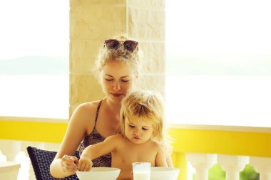 Masada oturuyordu terasta doğal zemin üzerine sütunlarla onun anneler plaka küçük çocuk yiyor.