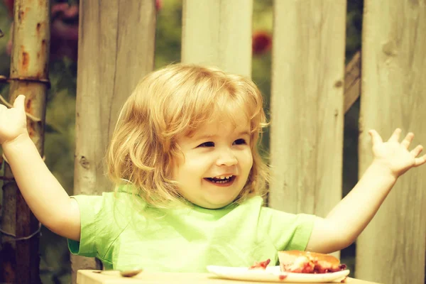 木製のフェンス近くのパイを食べる小さな男の子 — ストック写真