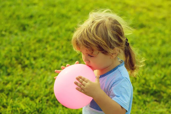 Menino brinca com balão de brinquedo rosa — Fotografia de Stock