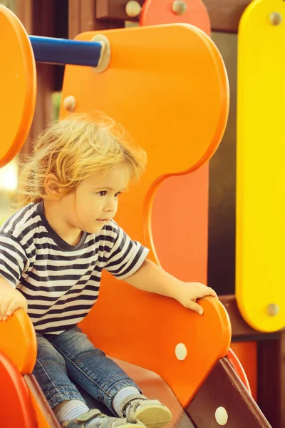 Şirin bebek çocuk turuncu slayt kurulu üstüne oturuyor