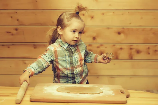 Carino bambino cucina con pasta e farina, tiene stampo metallico — Foto Stock